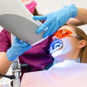 A woman undergoes teeth whitening and the application of a UV lamp for the bleaching process