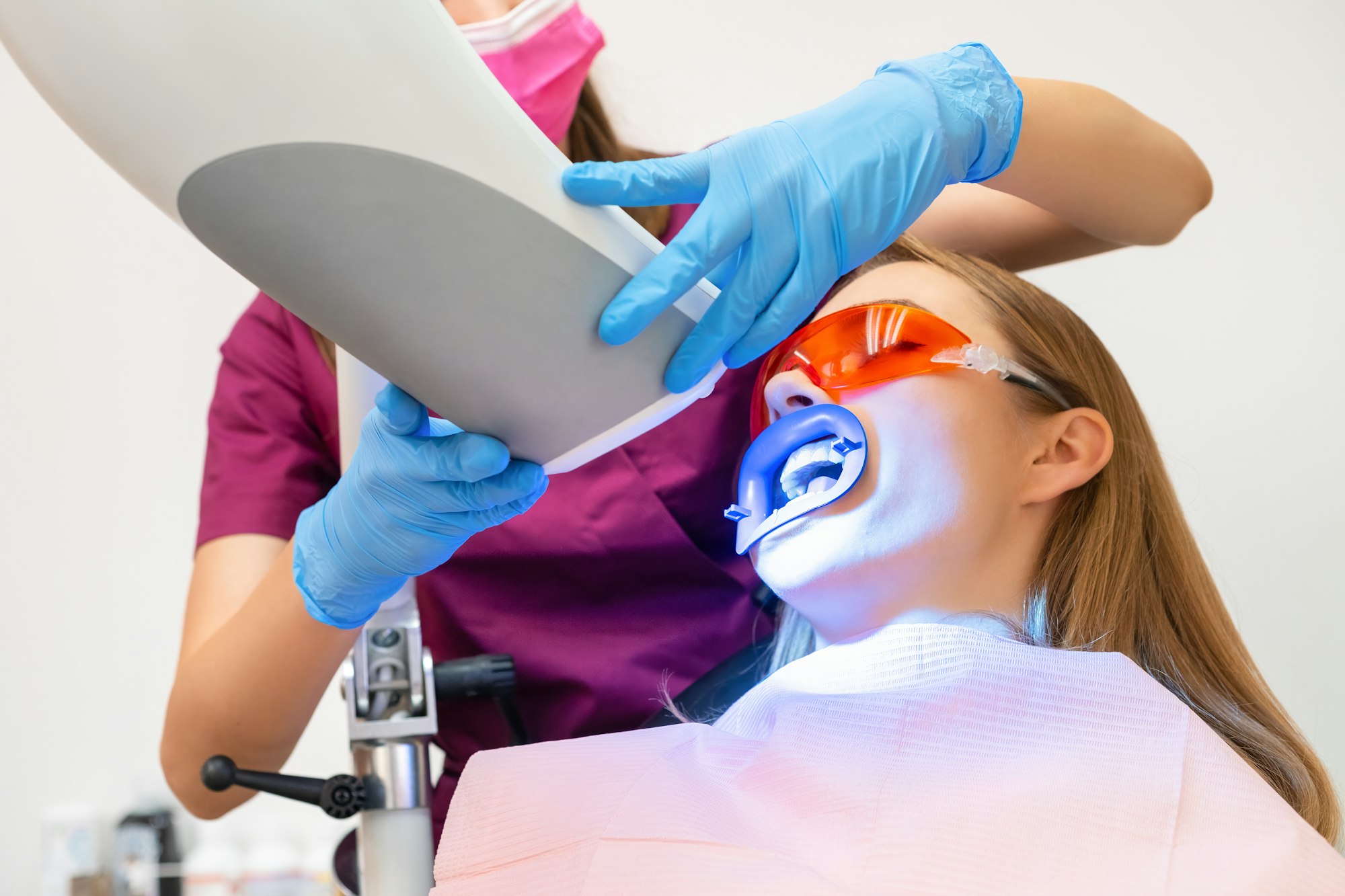 A woman undergoes teeth whitening and the application of a UV lamp for the bleaching process